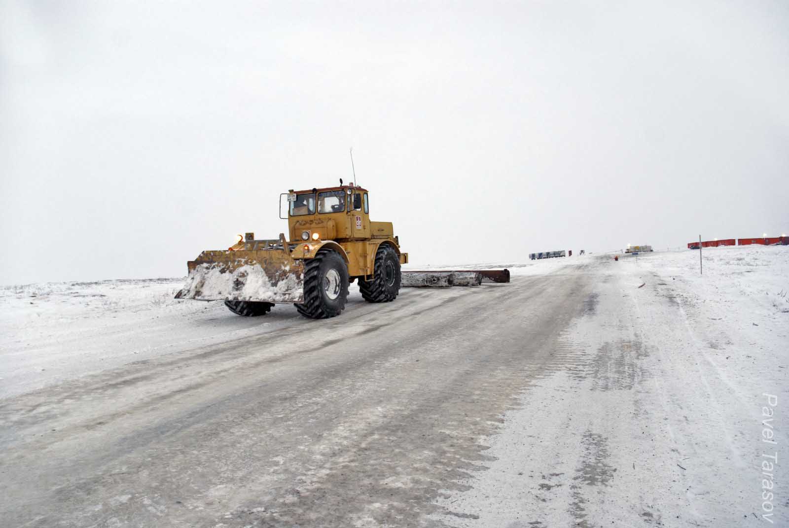Бульдозер равняет зимник. Сзади привязаны три трубы